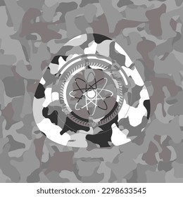 atom icon inside grey camouflaged emblem. 