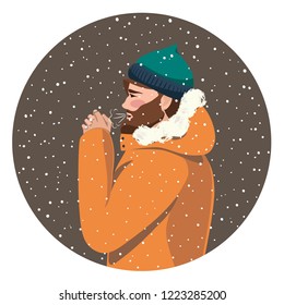 Attractive bearded young man standing and blowing on his hands outdoors in cold weather. Winter season. 