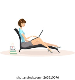 Attractive woman wearing glasses working on her laptop computer at home. Mug with words I love my job on it standing on pile of books nearby.
