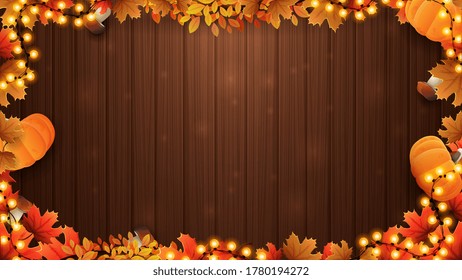 Autumn background with brown wooden wall and frame made of autumn leafs and autumn harvest elements