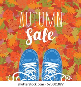 Autumn banner with the inscription Autumn sale and blue shoes on the background of  texture of colorful autumn leaves