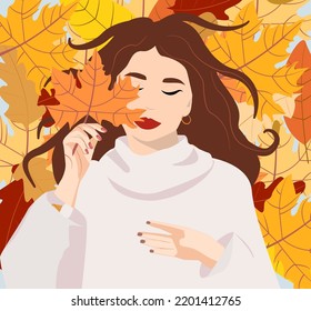 Autumn concept. A woman in a warm sweater lies on autumn leaves. The girl is holding a yellow autumn leaf in her hands. Colored pattern of autumn leaves. Suitable for a postcard or social network