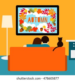 Autumn. Couple and cat watching television sitting on couch. 