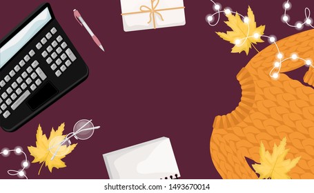 Autumn flat lay with the sweater, gift, laptop, lights, notebook and autumn leaves.