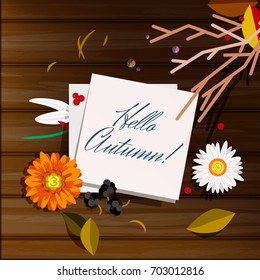 Autumn greeting card, background, backdrop. A note with Hello Autumn! lettering on a wooden table with beautiful flowers (Chammomile, marigold), berries and leaves