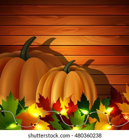 autumn leaves and two orange pumpkins with patio lights on wooden texture. Could be used for your Thanksgiving greetings