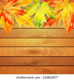 Autumn maple leaves on a background of wooden planks 
