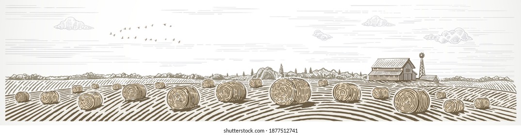 Autumn rural landscape in panoramic format with a farm and bales of hay in the foreground