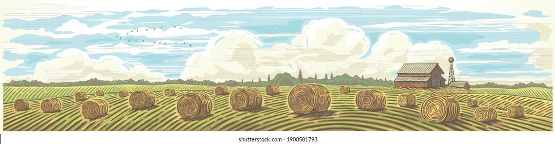 Autumn rural landscape in panoramic format with a farm and bales of hay in the foreground