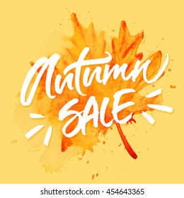 Autumn Sale inscription for special offer banners, season sale posters, discount tags. Handwritten brush lettering on hand painted watercolor orange leaf background.