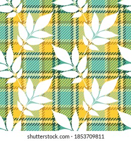 Autumn seamless pattern of ash fraxinus excelsior leaves white silhouettes on checkered tartan plaid textile background of green and yellow colors