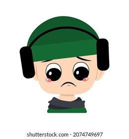 Avatar of child with big eyes and sad emotions, depressed face, down eyes in green hat with headphones. Cute kid with melancholy expression in winter headdress and scarf. Head of adorable baby