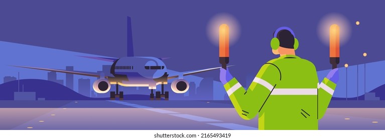 aviation marshaller with light sticks near aircraft air traffic controller airline worker in signal vest professional airport staff