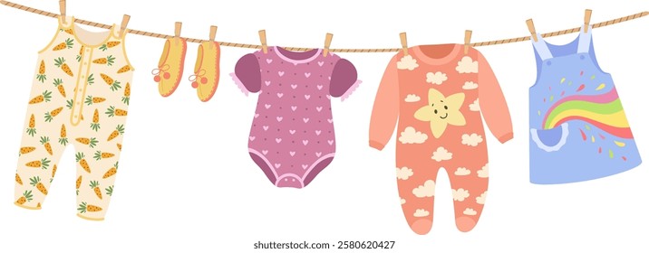 Baby clothes hanging on a clothesline are drying in the sunlight, featuring charming patterns of carrots, hearts, clouds, and a vibrant rainbow, adding a playful touch to any nursery