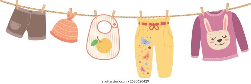 Baby clothes are hanging on a clothesline including shorts, a hat, a bib, pants and a sweater with a cute bunny design, suggesting laundry and childcare