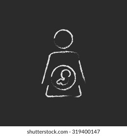 Baby fetus inside of mother icon hand drawn in chalk on a blackboard vector white icon isolated on a black background.