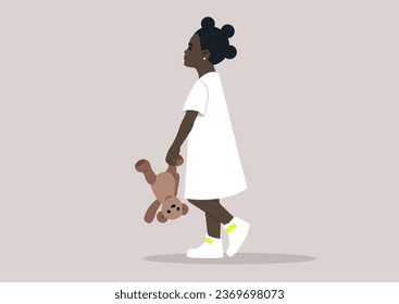 A baby girl in a white dress playfully holding a teddy bear upside down by its paw
