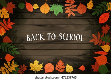 Back to School. Autumn leaves are drawn on the blackboard. Fall of the leaves. On wooden background.