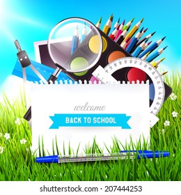 Back to school background with school supplies in the grass 