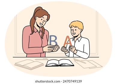 Back to school concept with boy learning alphabet along with elementary school teacher standing near table with books. Woman teaches child read or spell correctly, wanting give son quality education