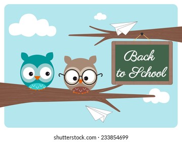 back to school, couple of small owls on a branch with a green chalkboard during a sunny day