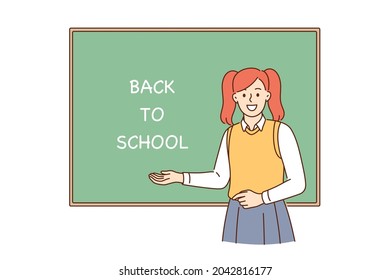Back to school and learning concept. Young smiling girl pupil cartoon character standing near blackboard with lettering on it showing excitement vector illustration 