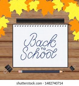 Back to school lettering hand written in a notebook. Wooden texture background and fall leaves. Vector template for advertising poster, logo design, greeting card, banner, flyer, sign, invitation, etc