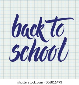Back to school words hand written by brush, blue over squared notebook page.