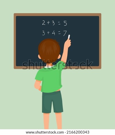 Back view of cute little boy student write on blackboard math equation in front of class with chalk