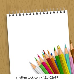 Background with color pencils. Empty notebook with color pencil on the table