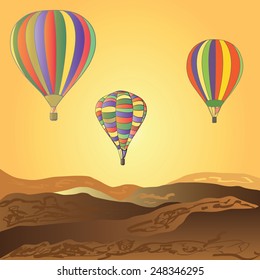 Balloons fly over the desert. Sunset.
