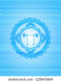 barbell on rack icon inside sky blue water wave emblem background.