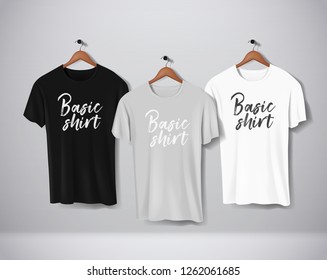 Basic Black, gray and white short sleeve T-Shirts Mock-up clothes set hanging isolated on wall. Front side view with lettering for your design or logo. 