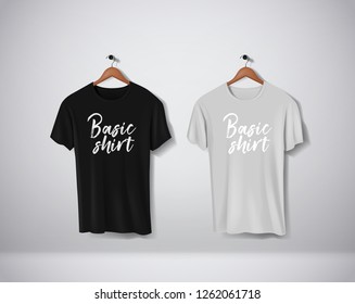 Basic T-Shirts collection. Black and gray Mock-up clothes set hanging isolated on wall. Front side view with lettering for your design or logo. 