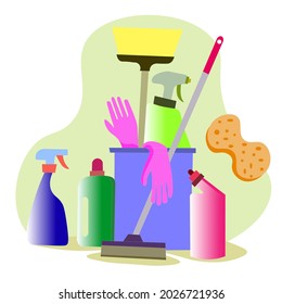 Basket with cleaning products for home and kitchen on a green kitchen background. A plastic bucket with a mop, hygiene items in the room.  The concept of cleaning.