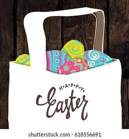 Basket with Easter colorful eggs. Happy Easter calligraphy. Wooden board background. Easter postcard.