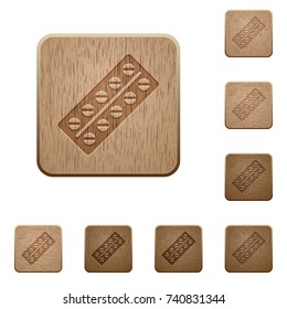Batch of pills in blister pack on rounded square carved wooden button styles