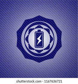 battery charging icon inside emblem with denim texture