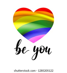 Be you - black handwritten lettering with heart shape in colors of  LGBT rainbow flag isolated on white background. Modern vector design, decorative inscription, motivational poster.