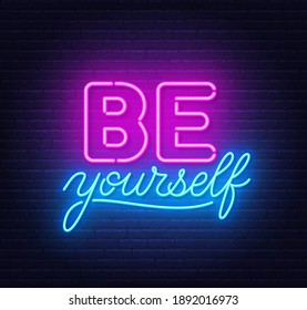 Be yourself neon inspirational quote on a brick wall.