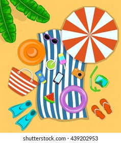 Beach Accessories top flat lay view on sand. Striped towel, umbrella, flip flops, flippers, float ring, snorkeling mask, bag, sunglasses, sun cream, hat, ice cream, watermelon. Have fun on a beach