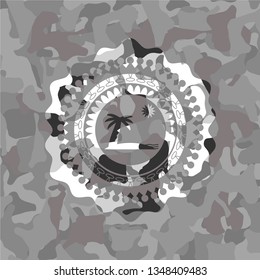 beach icon inside grey camouflaged emblem