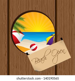 Beach seen through a hole on the wooden fence