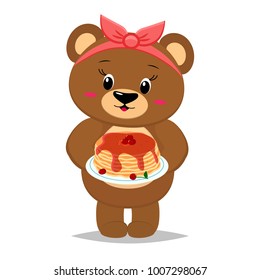 A bear with a red bow holds a plate of pancakes with maple syrup and cherries isolated on a white background.