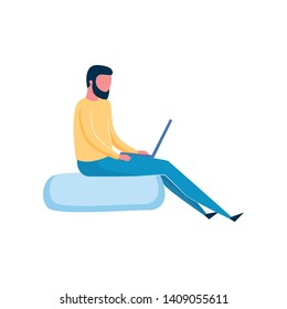 Beard man sitting at soft bag and working at his laptop