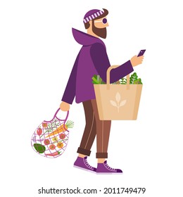 Bearded european man auf Null-Müll-Einkaufen. Nachhaltiger Lebenscharakter. Kaukasischer Mann ohne Kunststoff-Mesh-Einkäufer, braune Papiertasche mit frischem organischem Gemüse und Smartphone.
