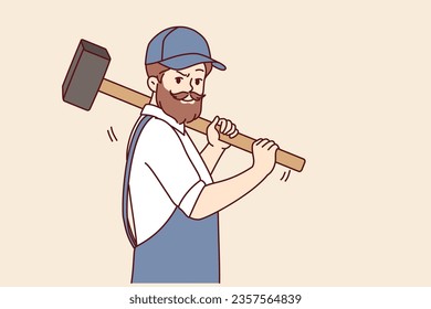 Bearded man with hammer works in auto repair shop or at construction site, dressed in overalls with cap. Brutal worker holding hammer offering to demolish old house and build modern mansion