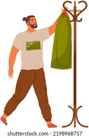 Bearded man stands in hallway removes his jacket from hanger with his hand, came home from work. Guy going for walk puts on jacket when leaving room. Isolated male character hangs clothes on hanger