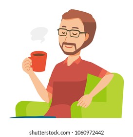 A bearded man wearing eyeglasses is sitting on a sofa and drinking coffee