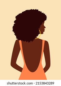 Beautiful african woman with curly hair in peach dress with open back looking over her shoulder